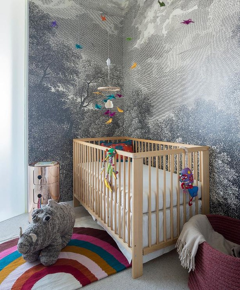 nursery with woodsy wallpaper and hanging accessories