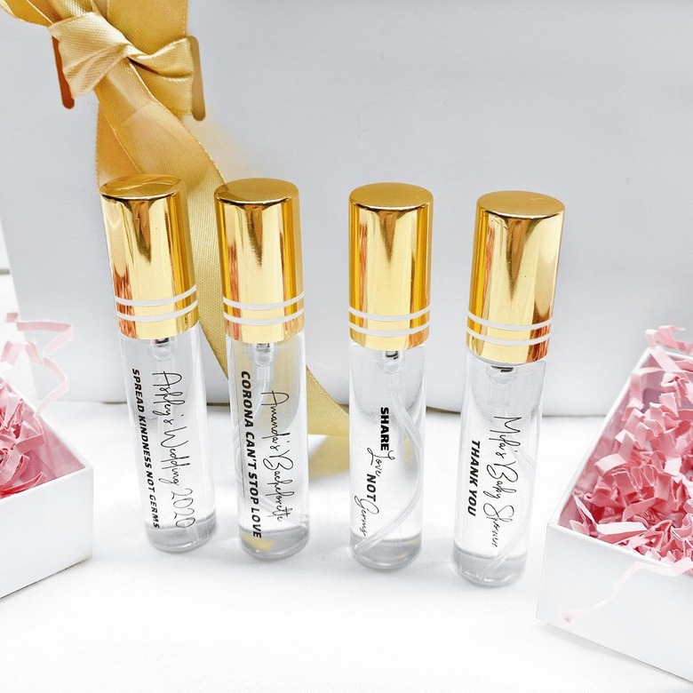 Four glass spray bottles with gold lids and custom text