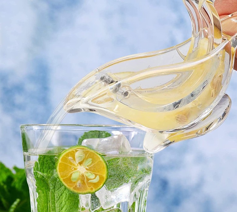 A bird lemon squeezer pouring lemon juice into a drink.