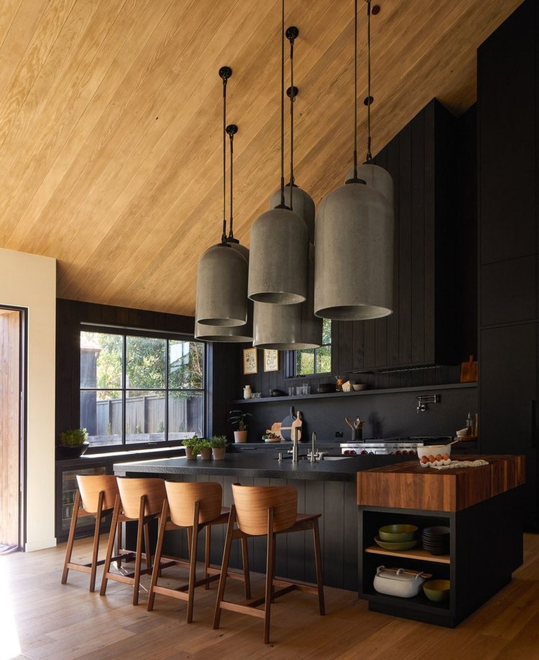 black kitchen island with oversize pendants hanging above