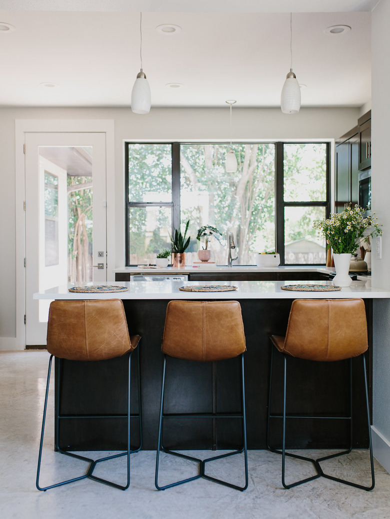 Black kitchen island with cognac leather stools.