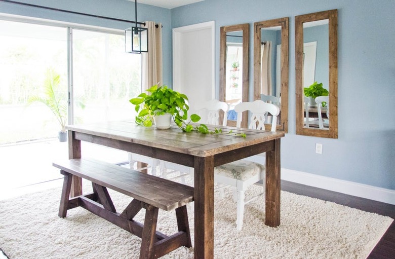 farmhouse-style dining table in room with blue walls and mirrors