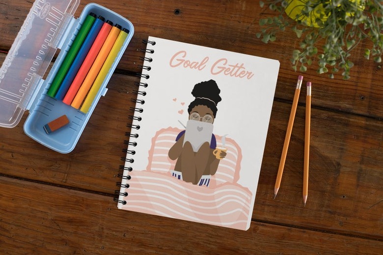 writing tools and notebook with illustrator and text that reads goal getter