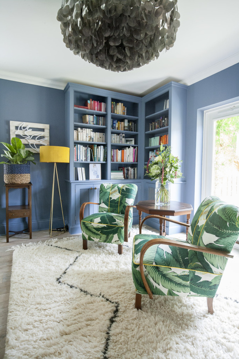 Blue bookcase blending in to blue living room walls with white shag carpet