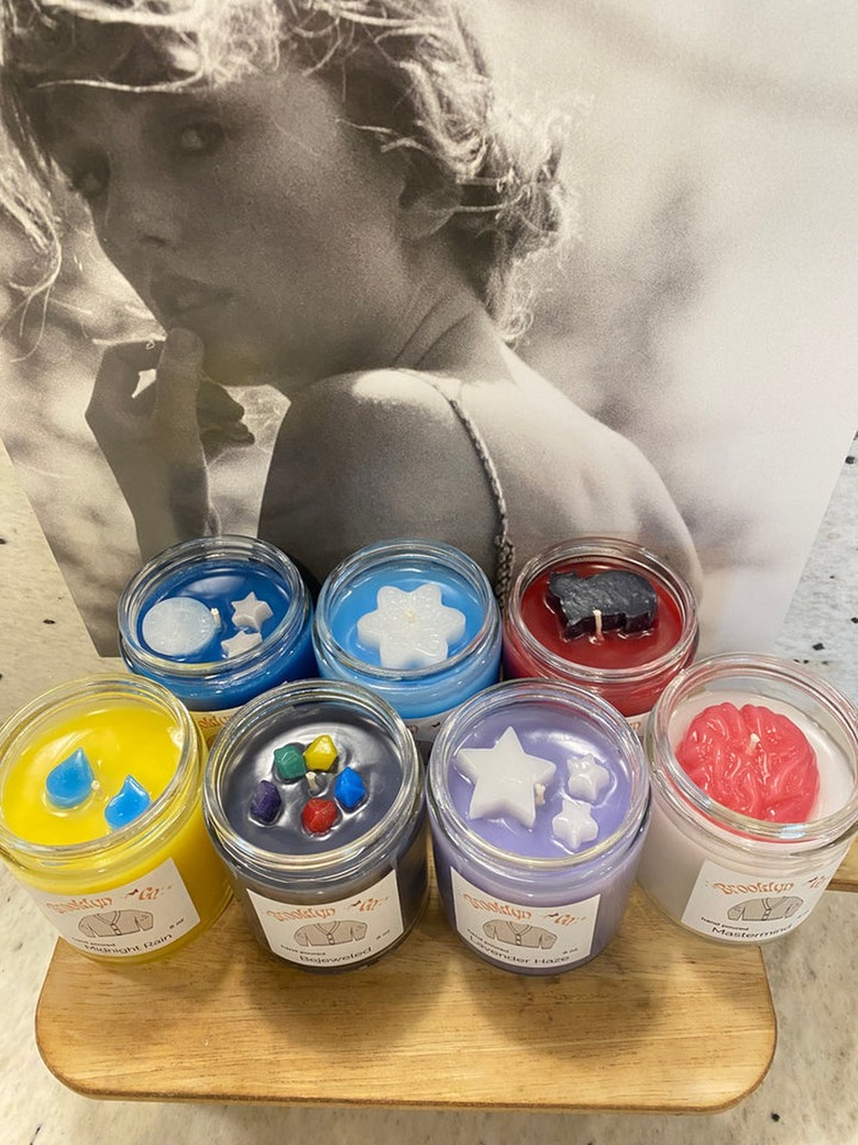 Seven candles from Brooklyn + Co's Taylor Swift collection rest on a wooden surface