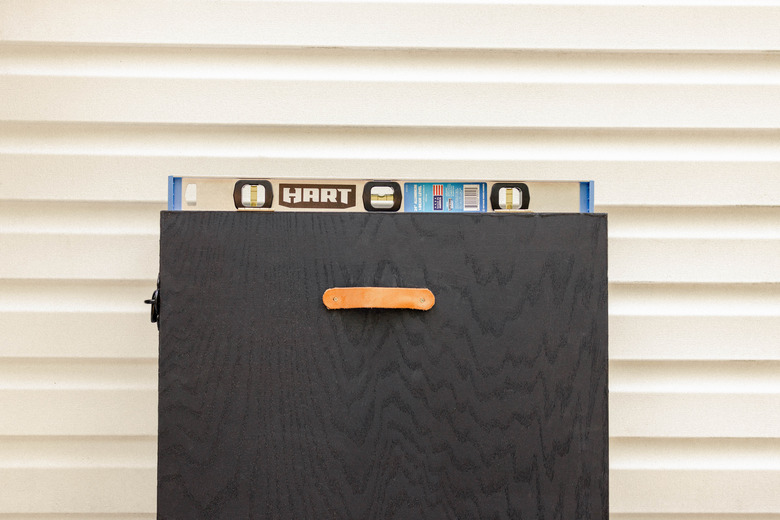 Cabinet held against wall with level on top to check for levelness