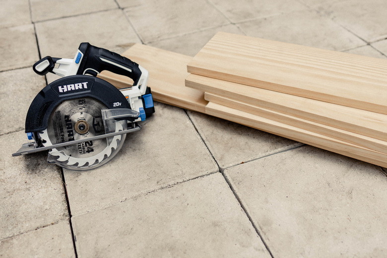 Wood boards stacked on patio floor next to HART circular saw