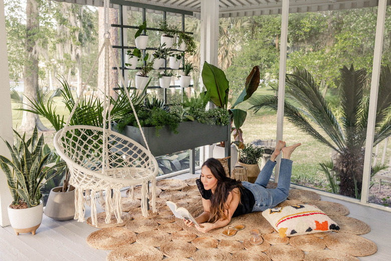Woman reading book on boho patio with trellis plant wall
