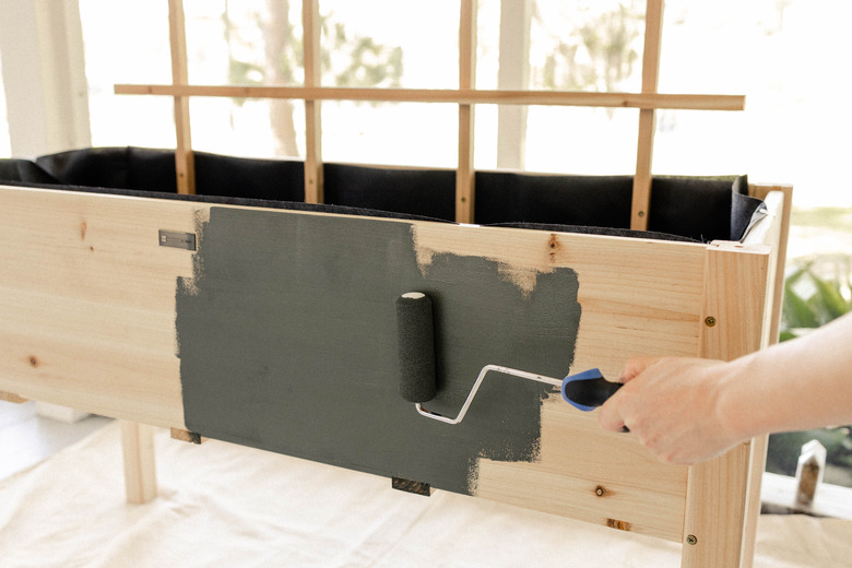 Painting dark olive green paint on planter box