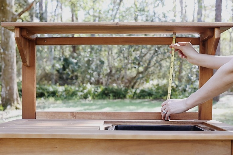 Measuring the opening on the potting bench with tape measure