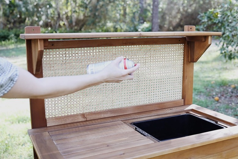 Spraying cane webbing with clear waterproof sealant