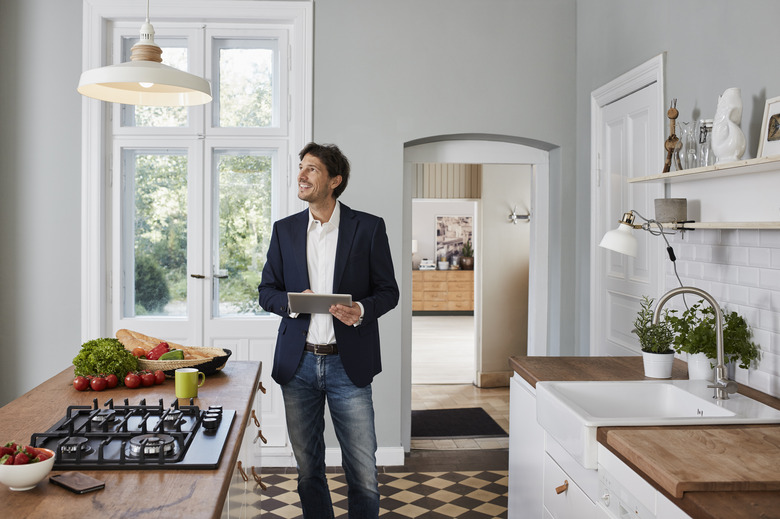 Man using tablet in kitchen looking at ceiling lamp