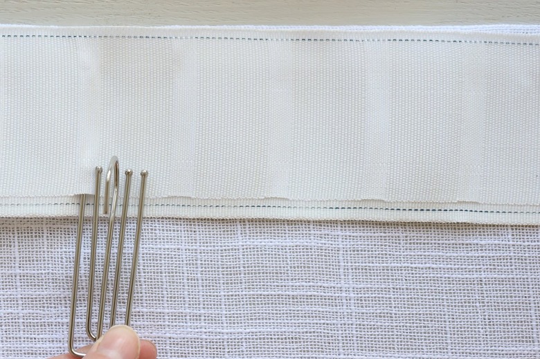 Inserting first prong of pinch pleat hook into pleater tape