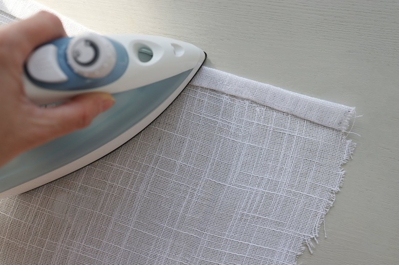 Ironing double hem on white linen fabric with no sew hemming tape