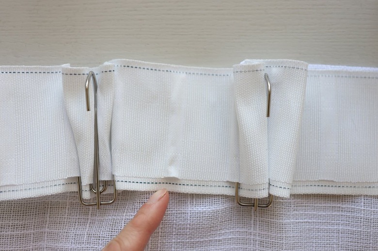 Two pleater hooks inserted into pleater tape with a space left open between them