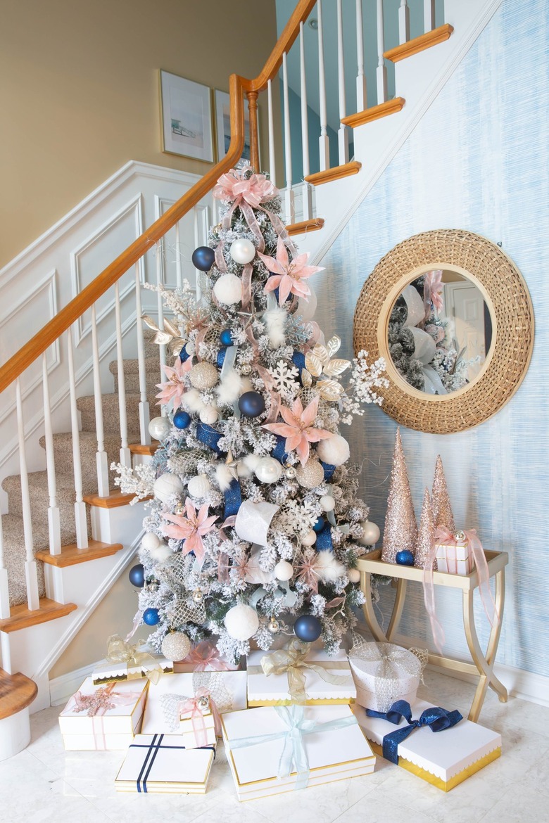 Foyer with silver Christmas tree with navy and pink ornaments and stars.