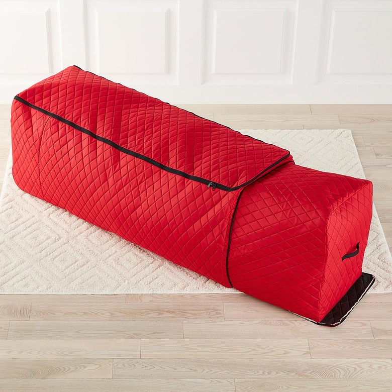 Red quilted Christmas tree storage bag with expandable option on white rug