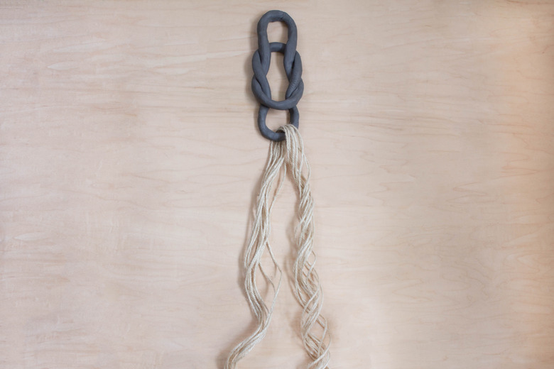 Feeding twine strands through clay oval