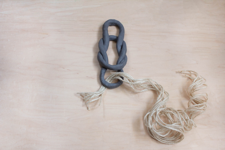 Feeding twine strands through clay oval