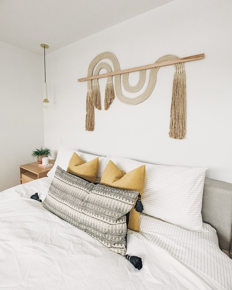 minimalist white bedroom with woven wall hanging