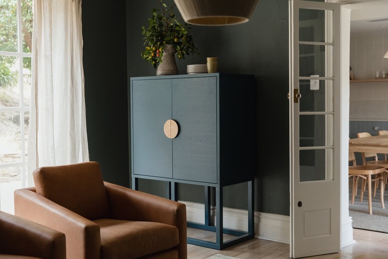 leather club chair sits beside a modern cabinet