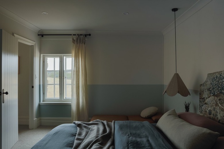 primary bedroom with blue wainscoting and bedside pendant
