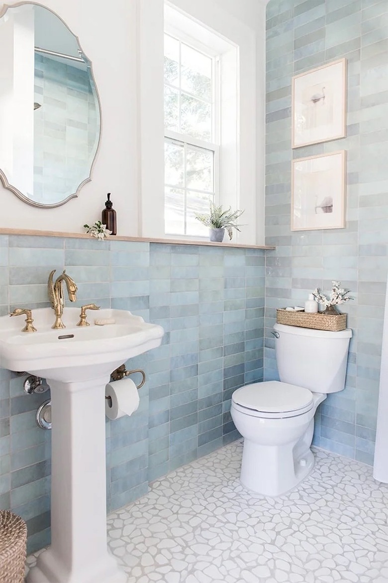 A small bathroom with blue wall tiles and pebble flooring