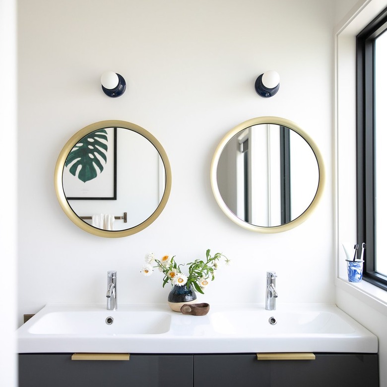 Navy blue coastal bathroom lighting idea above circular mirrors in white bathroom