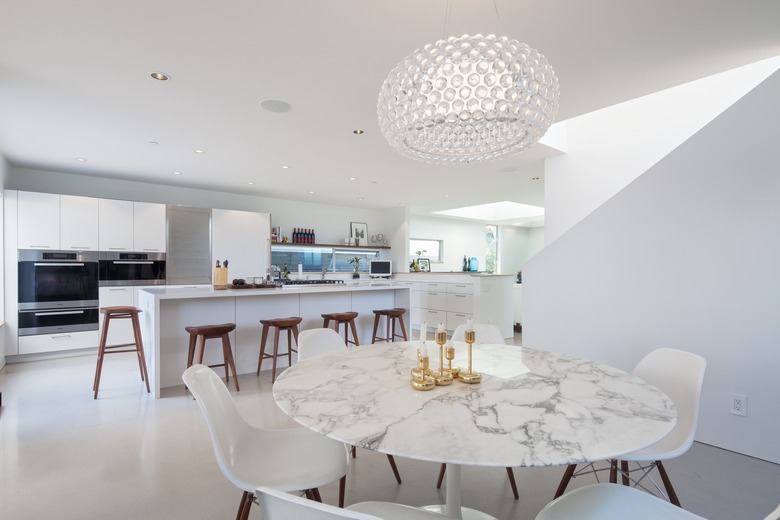 A marble Saarinen Tulip dining table is surrounded by Herman Miller Eames molded fiberglass side chairs in the dining area.