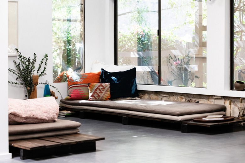 Minimalist living room with mauve daybed cushions on wood frame and patterned pillows