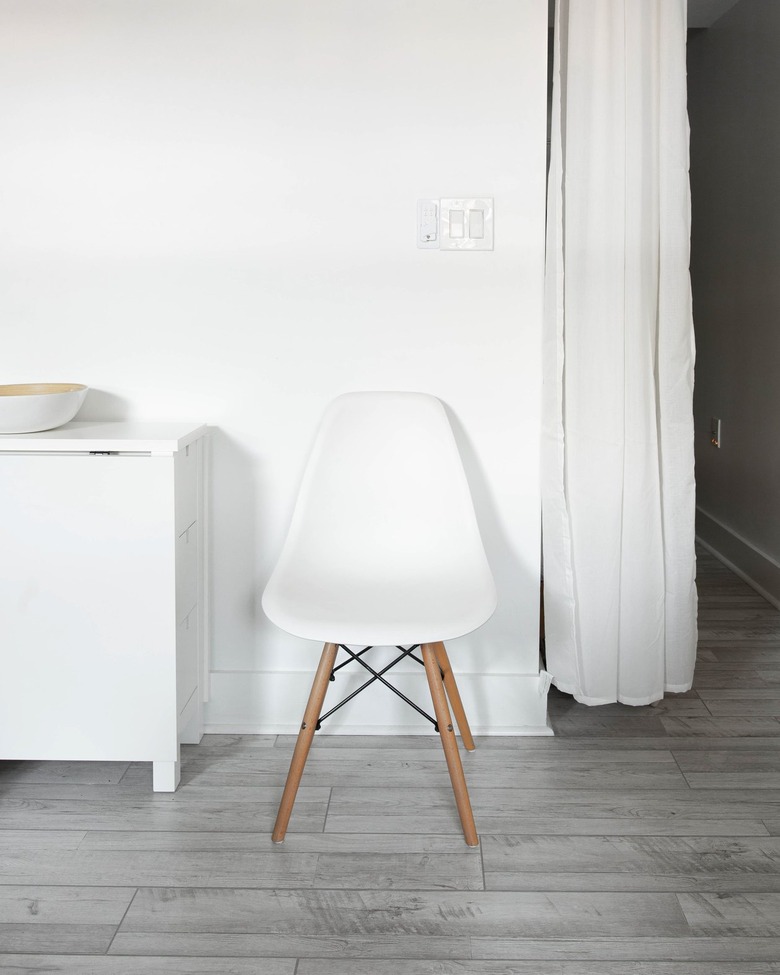White room with white chair and dresser and hanging white curtains