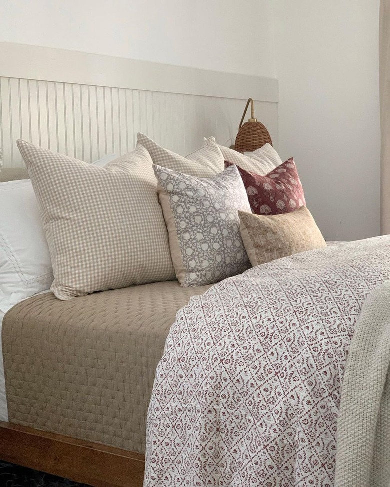 A bed with a white headboard and multiple decor pillows.