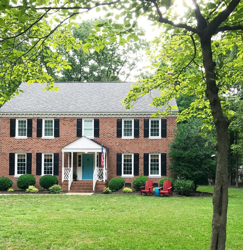 Brick house with teal blue door and black shutters