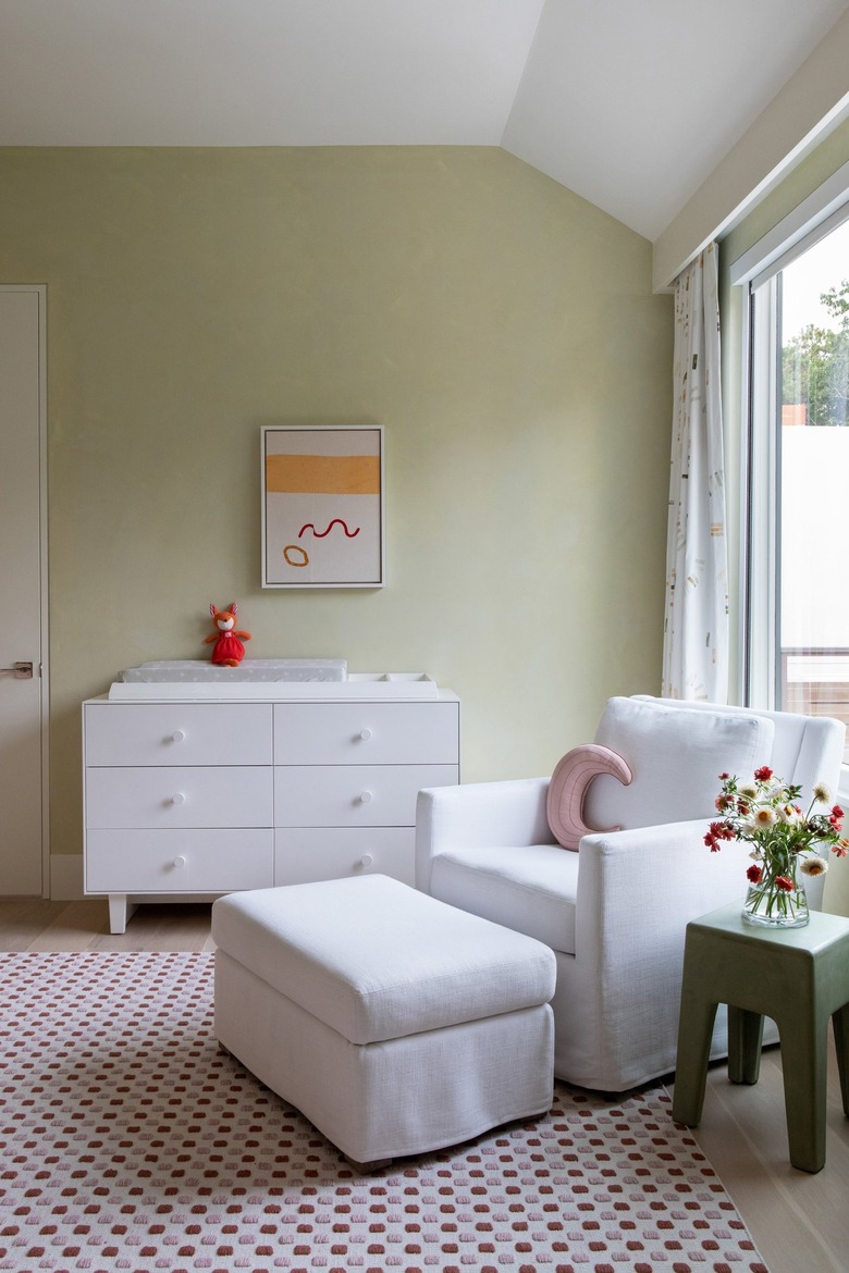 A light green nursery with white chair