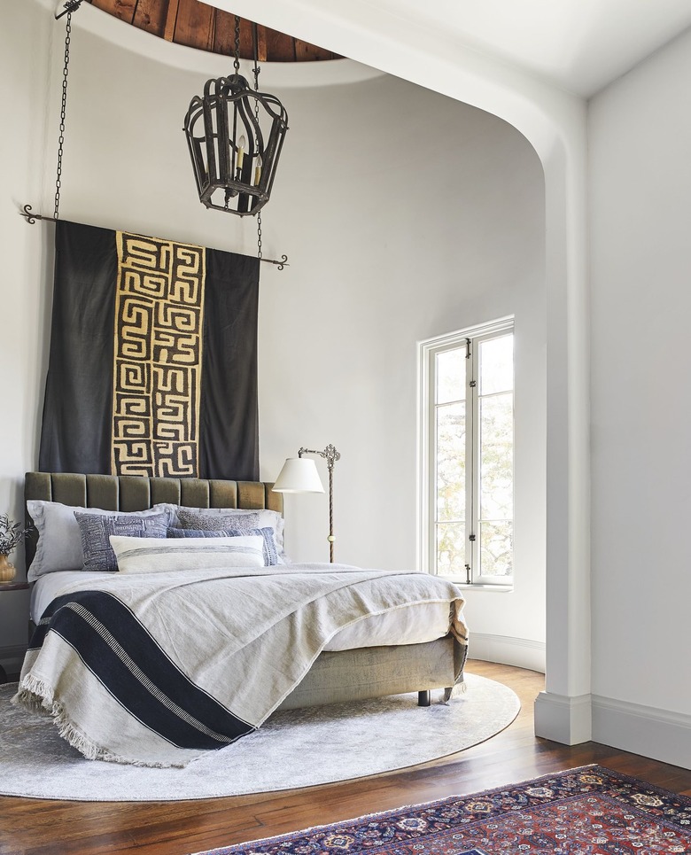 Gold design hangs over black and white bed