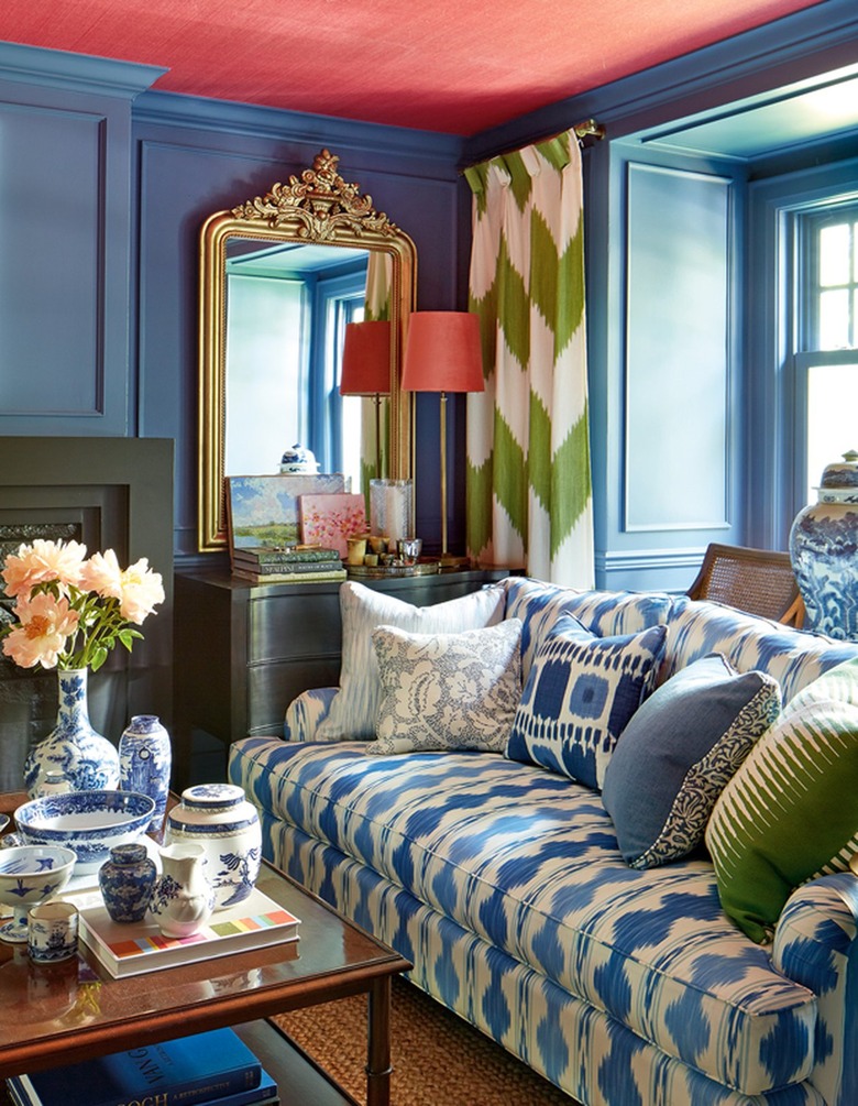 Blue living room with coral ceiling and green curtains and pillows.