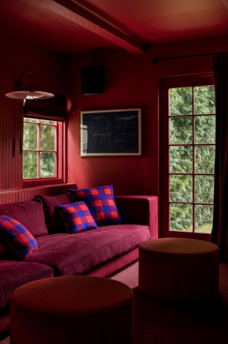 Living room with burgundy couch and red walls.