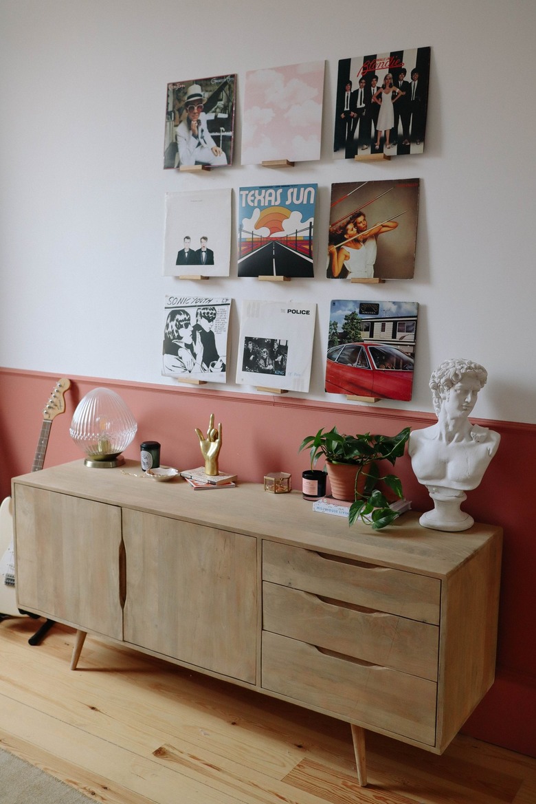oak sideboard in front of white and coral wall with vinyls on display