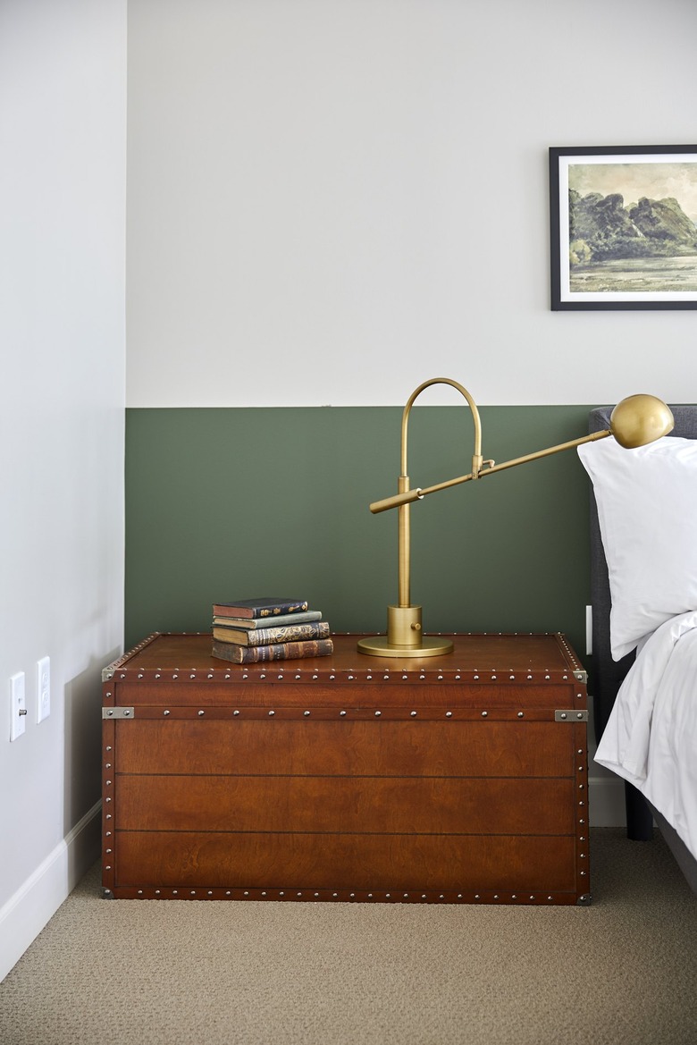 bedroom with brown trunk and gold lamp