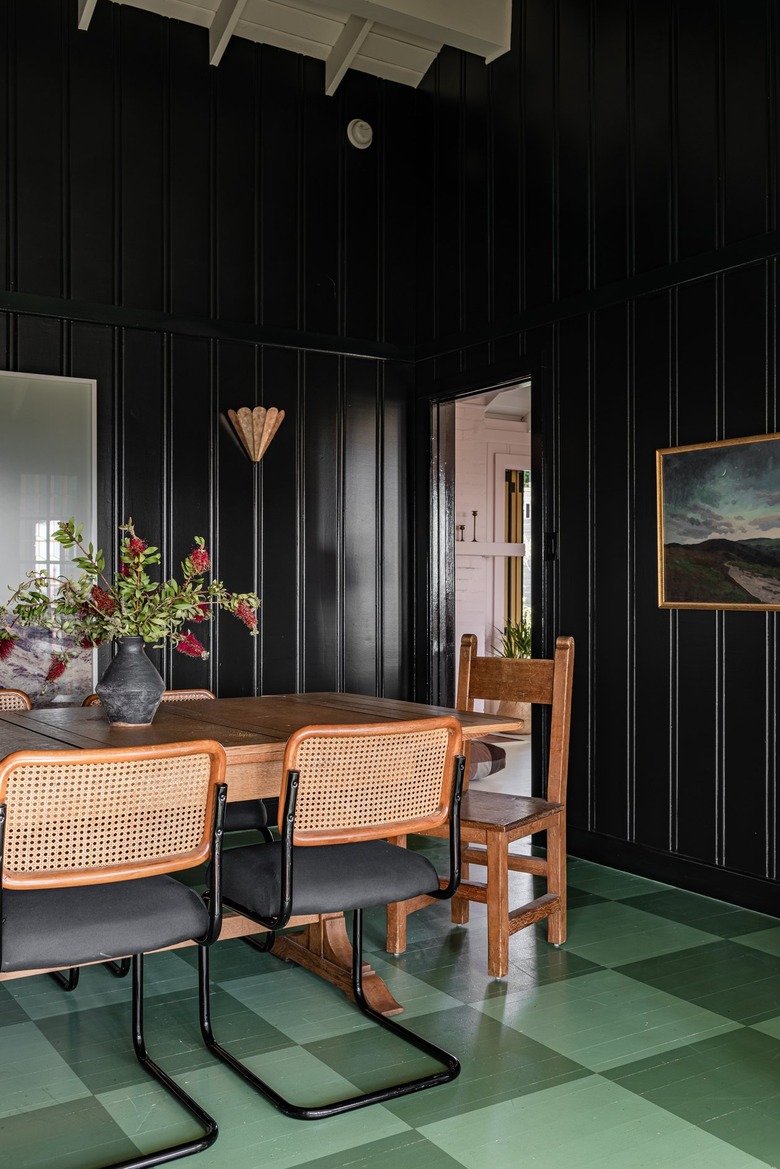 Black wall paneled dining room with a green checkerboard floor