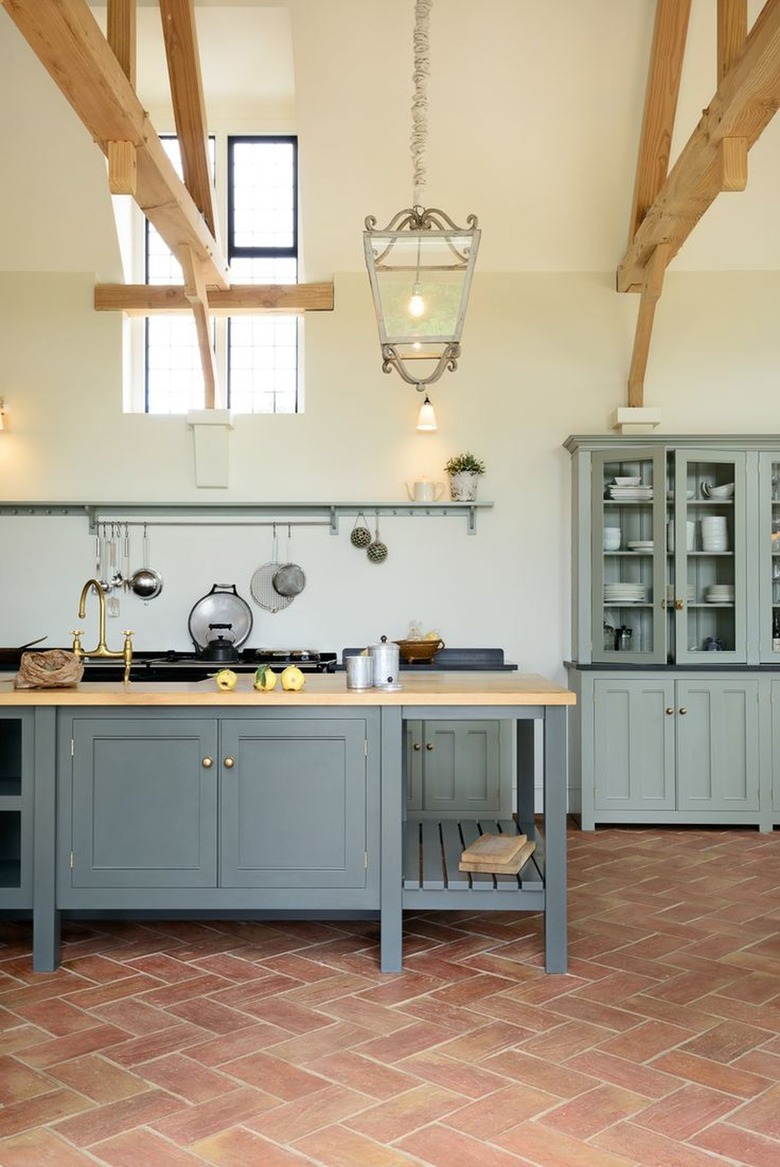 Kitchen with light blue cabinets and terracotta tile.