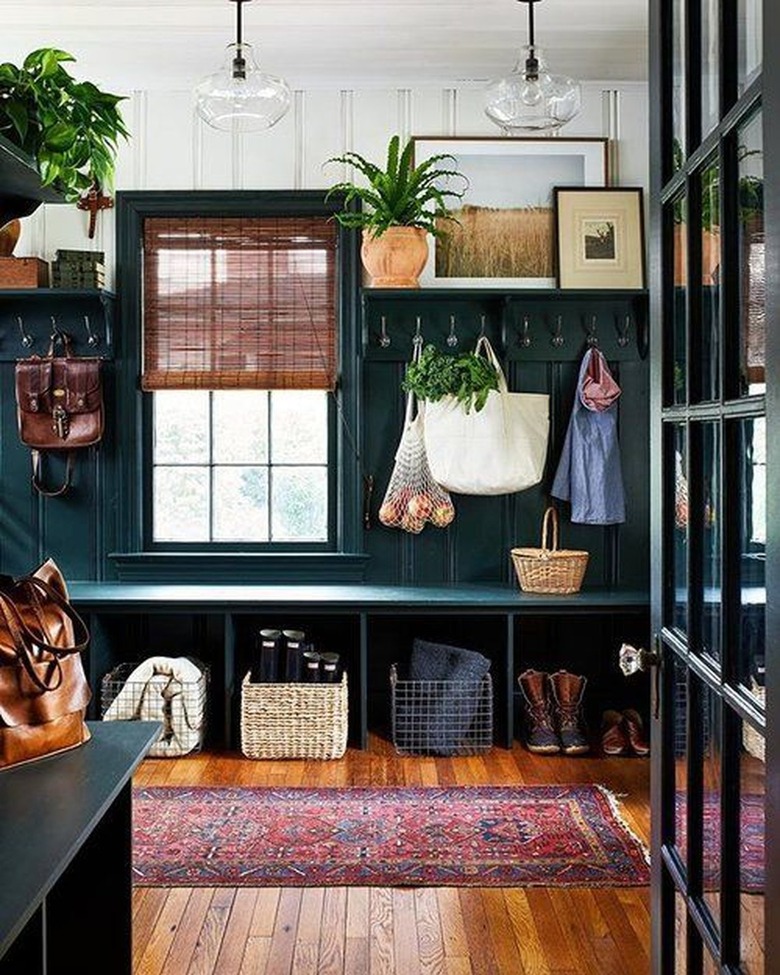 Mudroom with dark teal walls and maroon rug.