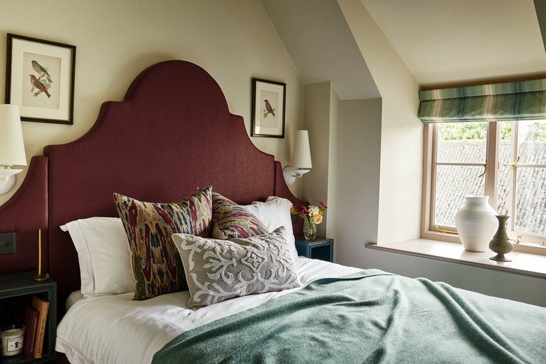 Bedroom with maroon headboard and blue-green comforter.
