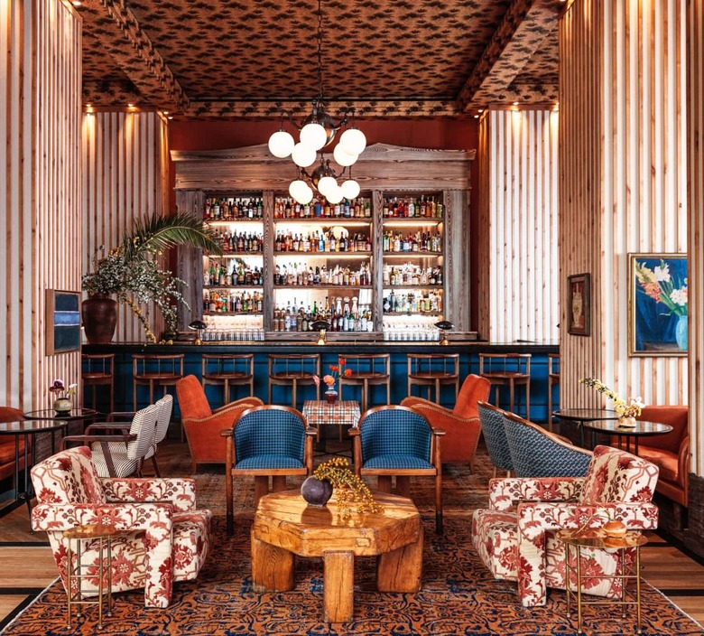 A mix of red-orange and blue printed textiles cover all the seating in the large lounge area of the Peacock Bar