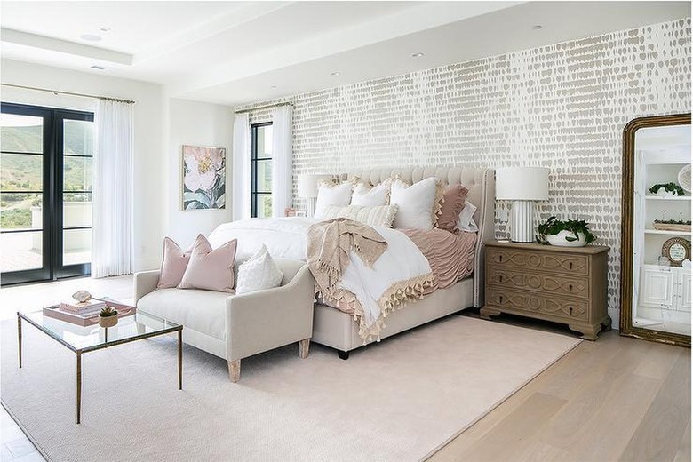 Bedroom with patterned wallpaper and pink bedding.