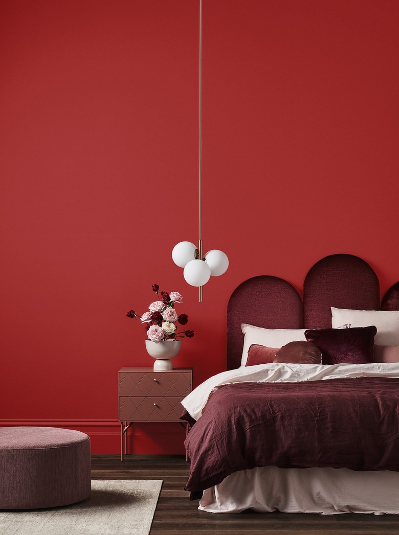 Bedroom with red wall and decorative burgundy headboard and comforter