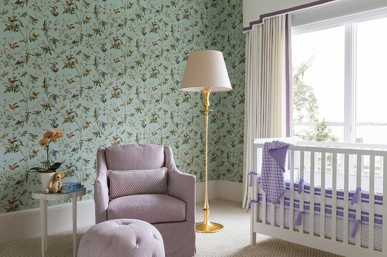 nursery with seafoam green wallpaper and lilac furniture