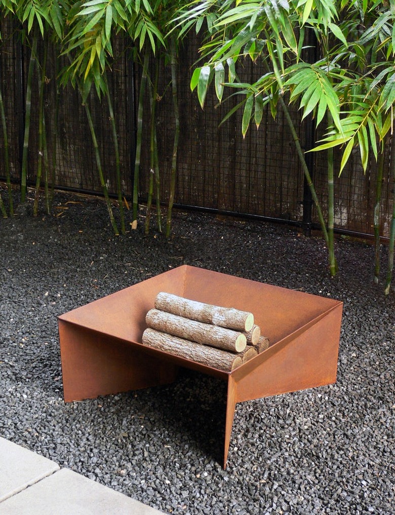 Geometric fire pit in rust sitting on gravel with logs