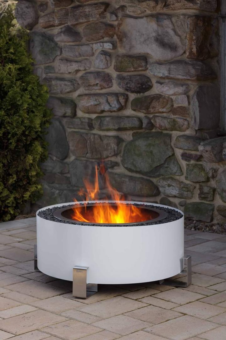 Sleek white contemporary fire pit against stonework