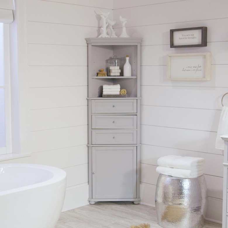 Gray corner bathroom cabinet with tub and wood-paneled walls